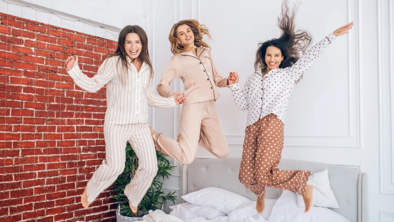 Femmes en pyjama sautant sur un lit